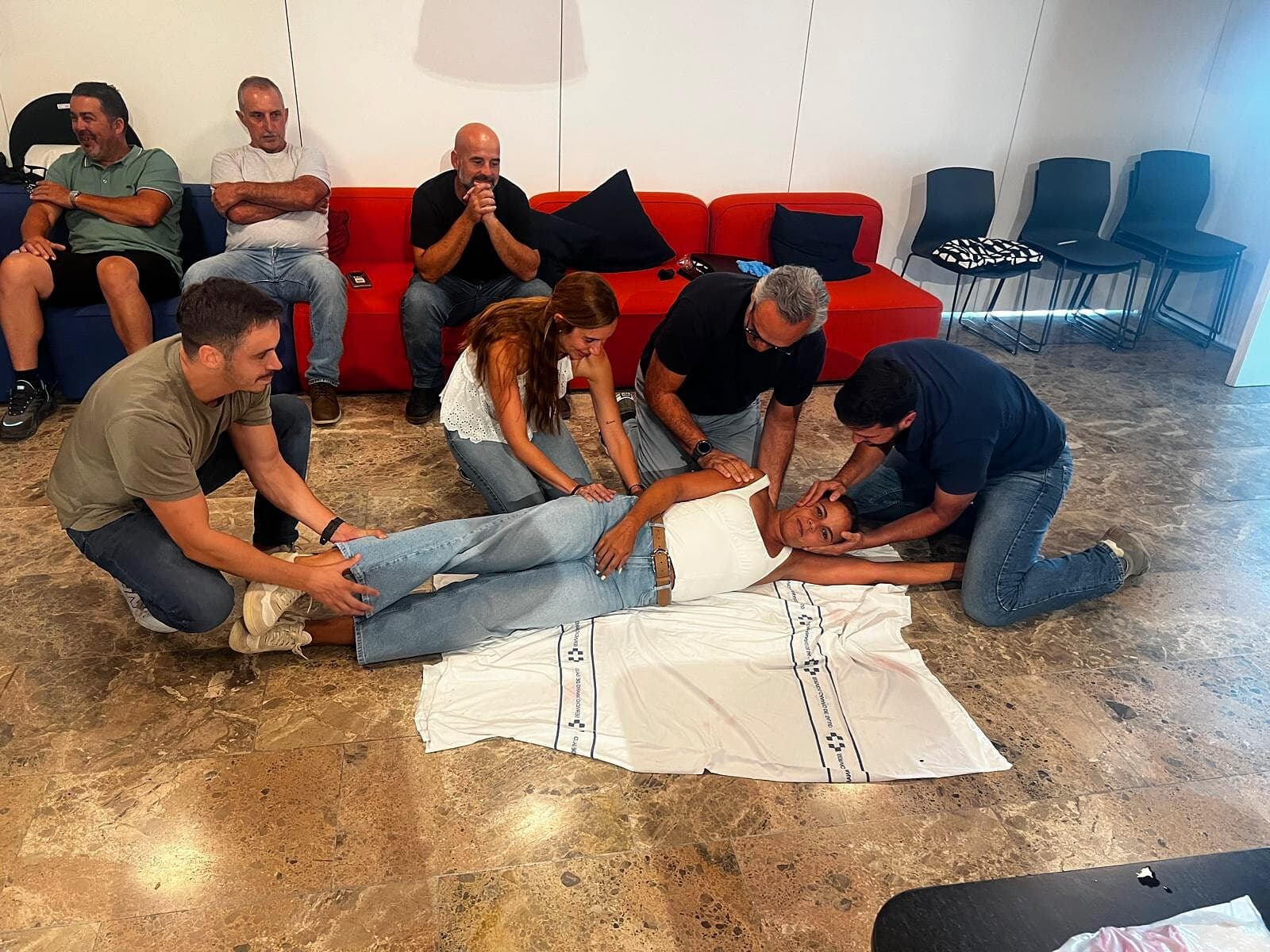 Grupo practicando una técnica de primeros auxilios en equipo durante una formación