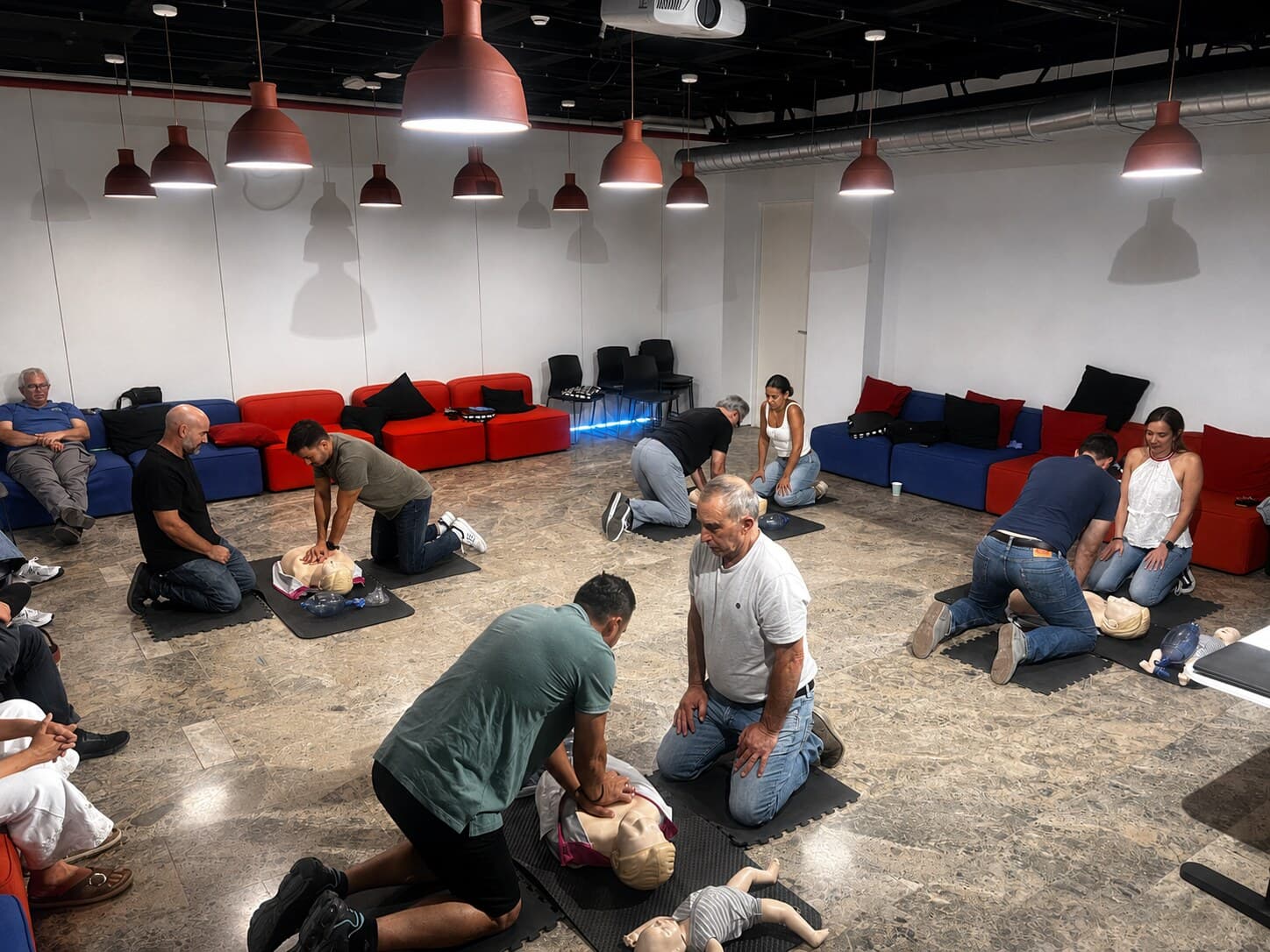 Grupo de trabajadores practicando reanimación cardiopulmonar (RCP) con maniquíes durante una formación